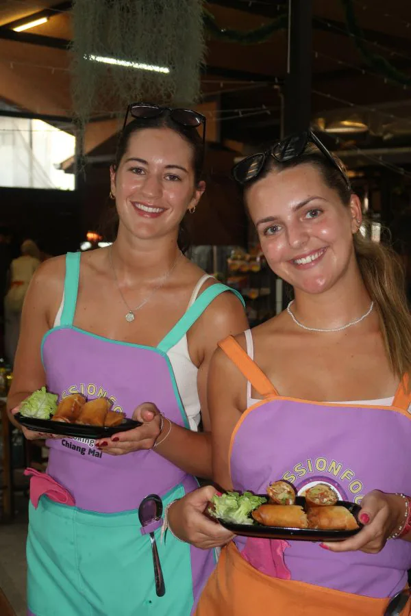 Two smiling students in colourful aprons