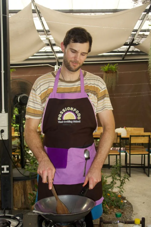 A student stir-frying at his wok under the school’s sail shades