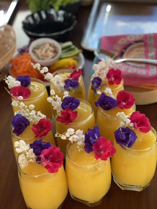 A row of golden drinks garnished with edible flowers
